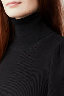 Woman wearing a black bishop sleeves pullover against a white background