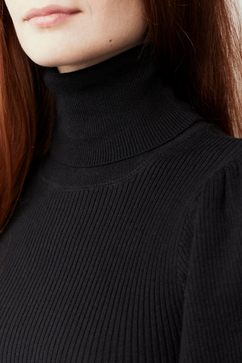 Woman wearing a black bishop sleeves pullover against a white background