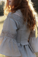 Woman in a natural linen dress and linen corset with linen lace standing among trees