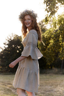 Woman in a natural linen dress and linen corset with linen lace standing among trees