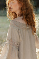 Woman in a natural linen dress with linen lace standing among trees