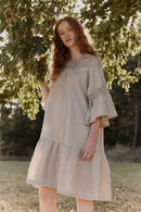 Woman in a natural linen dress with linen lace standing among trees