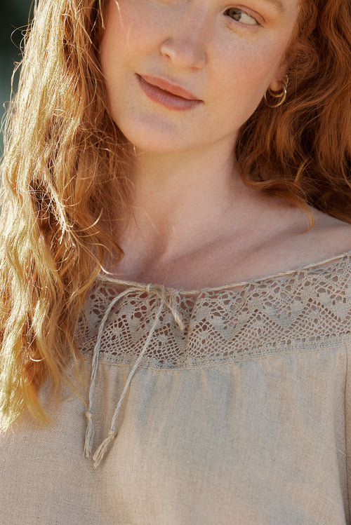Woman in a natural linen dress with linen lace standing among trees