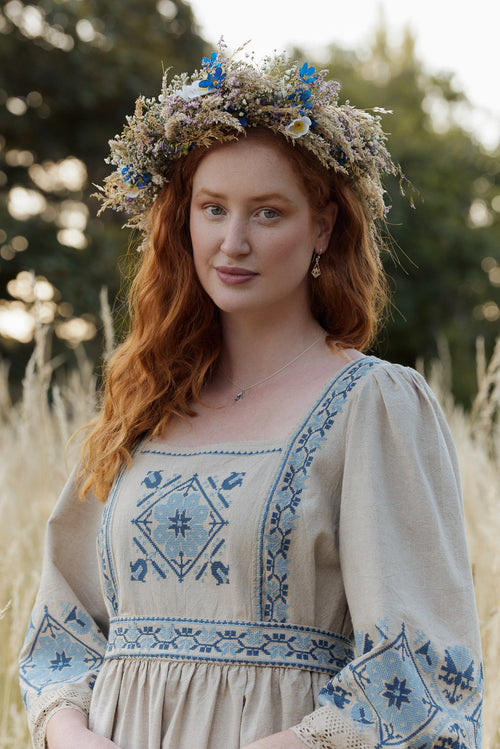 Woman in a traditional dress with floral crown standing in a field