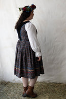 Plus size person wearing a traditional outfit with a floral headpiece against a plain background