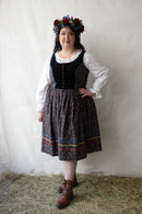 Plus size person wearing a traditional outfit with a floral headpiece against a plain background