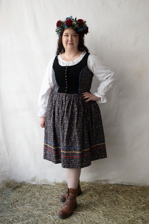 Plus size person wearing a traditional outfit with a floral headpiece against a plain background