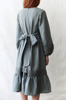 Person wearing a gray dress with a belt against a white background