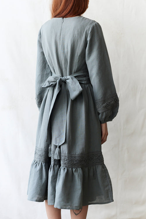 Person wearing a gray dress with a belt against a white background