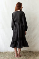 Woman wearing a black dress standing on straw with a white background