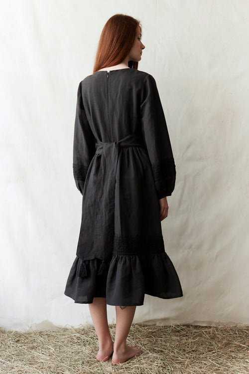 Woman wearing a black dress standing on straw with a white background