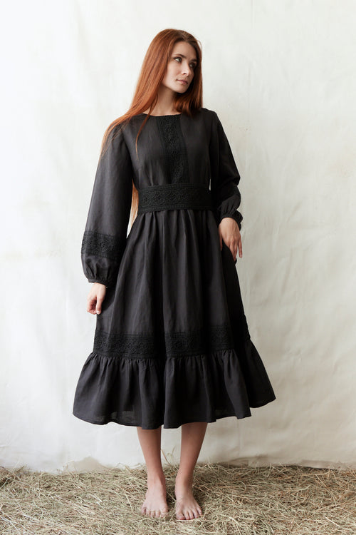 Woman wearing a black dress standing on straw with a white background