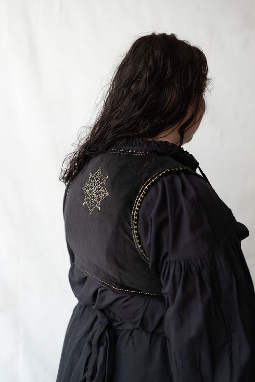 Plus size woman wearing a black dress with decorative elements against a white background