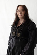Plus size woman wearing a black dress with decorative elements against a white background