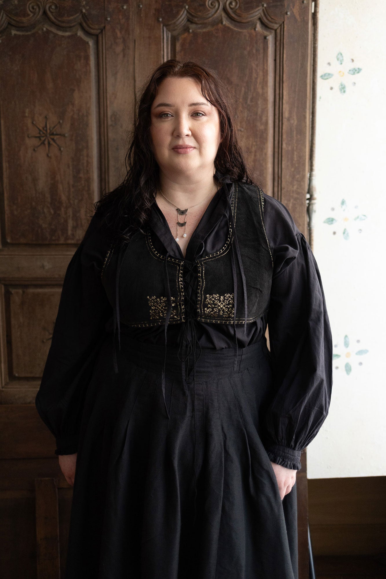 Plus size woman wearing a black dress with decorative elements against a white background