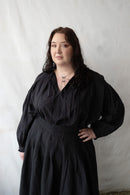 Person wearing a black dress against a plain background