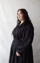 Woman wearing a black dress against a plain background
