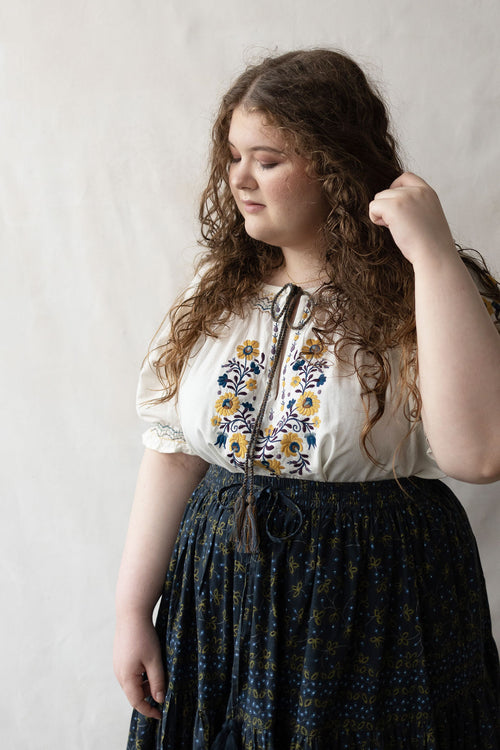 + size Woman wearing a white Hungarian Matyo blouse with floral embroidery against a plain background