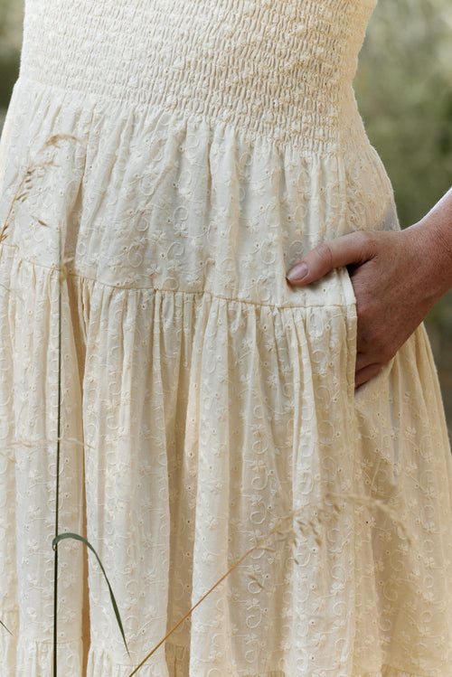 Beige dress with a hand in the pocket against a blurred natural background