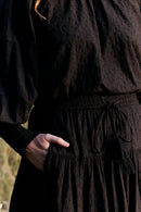 Person wearing a dark brown dress with a blurred background