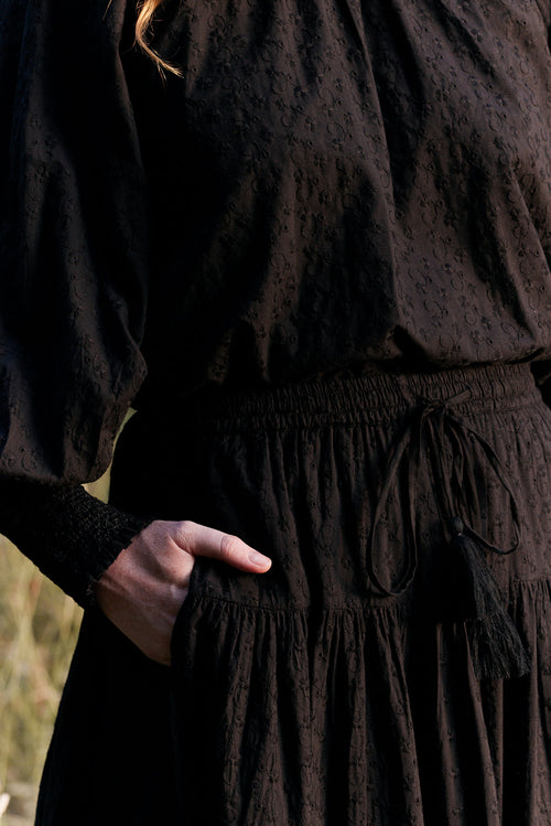 Person wearing a dark brown dress with a blurred background