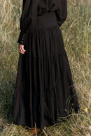 Person wearing a long black dress standing in a grassy field