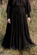 Person wearing a long black dress standing in a grassy field