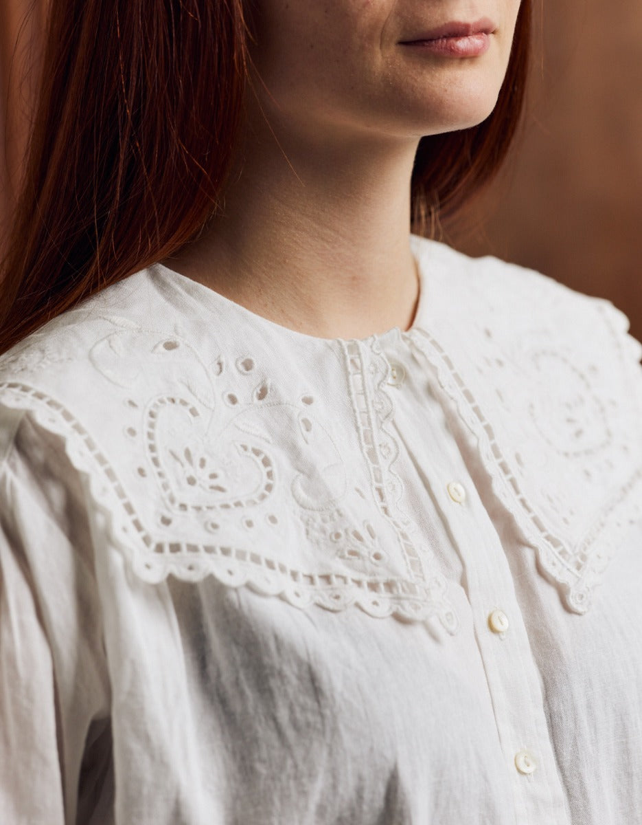 Close-up of a person wearing a white blouse with intricate lace detailing.