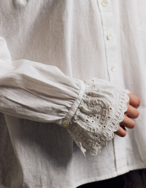 Close-up of a white shirt with lace cuffs and trim.