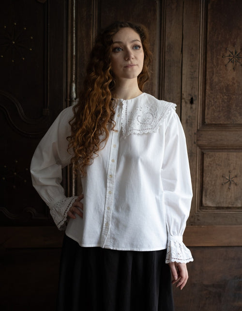 Woman wearing a white blouse with lace details in a rustic setting