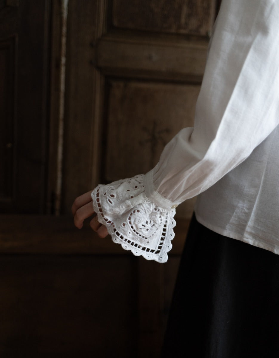 White blouse with lace cuffs against a wooden background