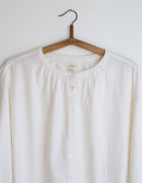 White blouse on a wooden hanger against a white background