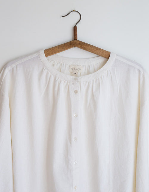 White blouse on a wooden hanger against a white background
