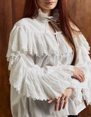 Woman wearing a white lace blouse against a wooden background
