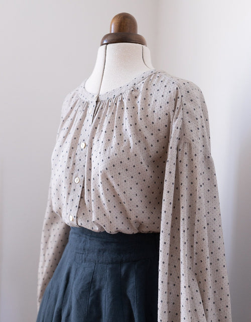 Polka dot blouse on a mannequin against a plain background
