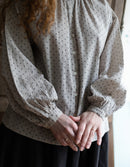 Person wearing a polka dot blouse with long sleeves indoors