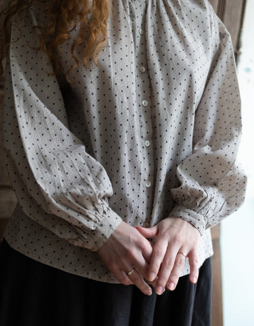 Person wearing a polka dot blouse with long sleeves indoors