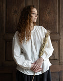 Woman in a white blouse holding a broom against a wooden door