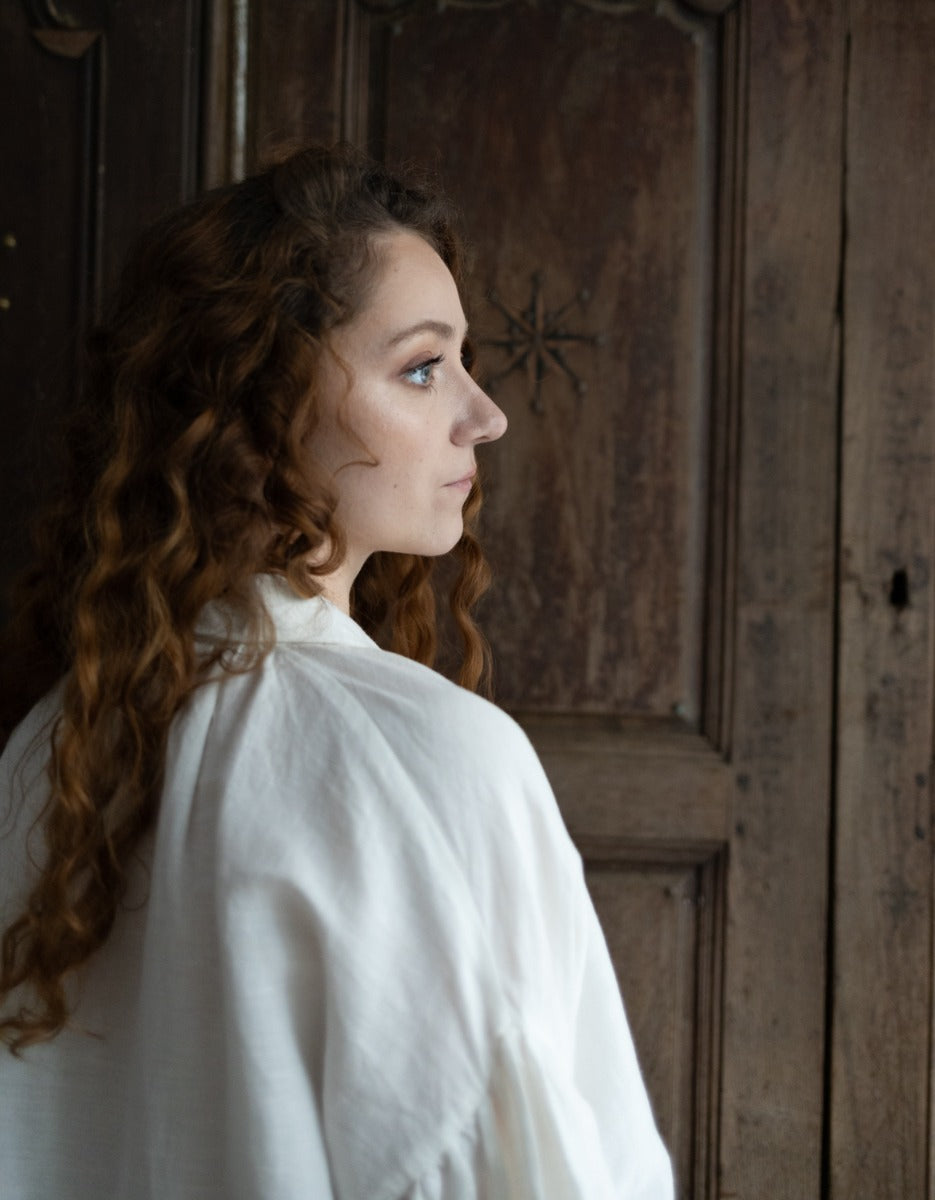 Woman in a white coat standing in front of a wooden door