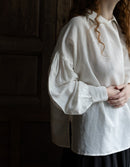 Person wearing a white shirt with long sleeves against a dark background