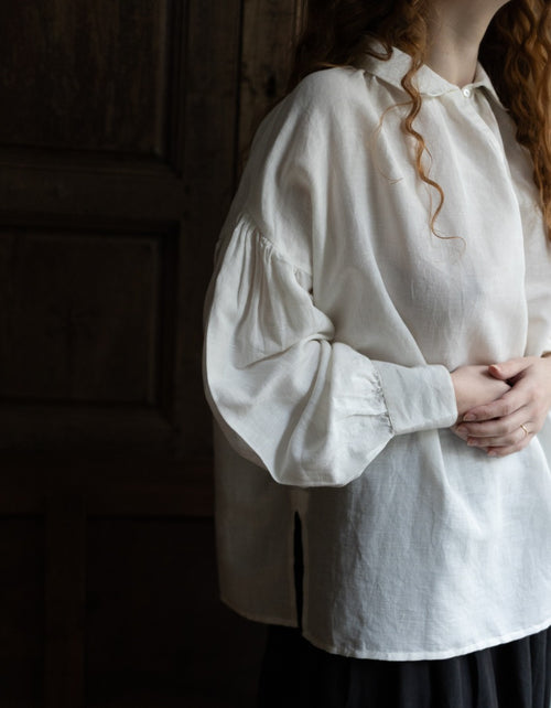 Person wearing a white shirt with long sleeves against a dark background