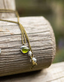 Necklace with a green pendant and silver beads on a wooden surface