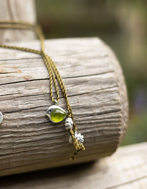 Necklace with a green pendant and silver beads on a wooden surface