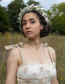 Woman wearing a floral crown and white dress in a natural setting